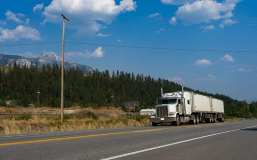 Semi-trailer truck drives along rural road