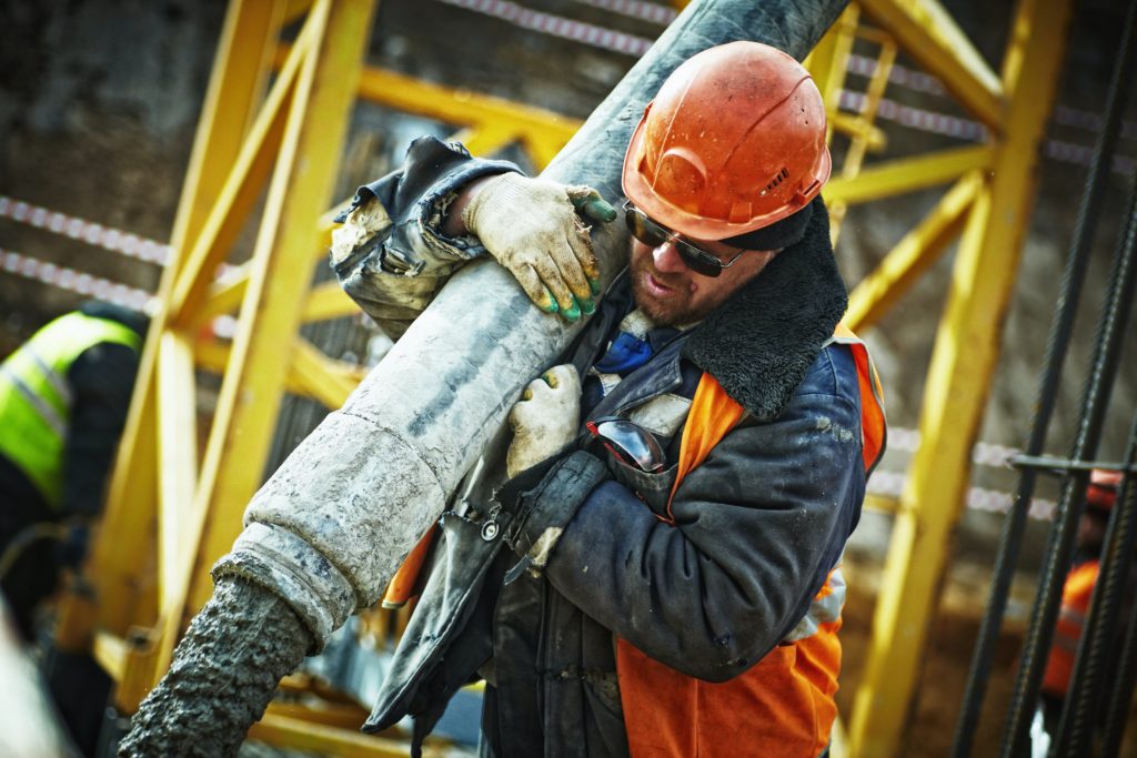 Construction worker lifting pipe