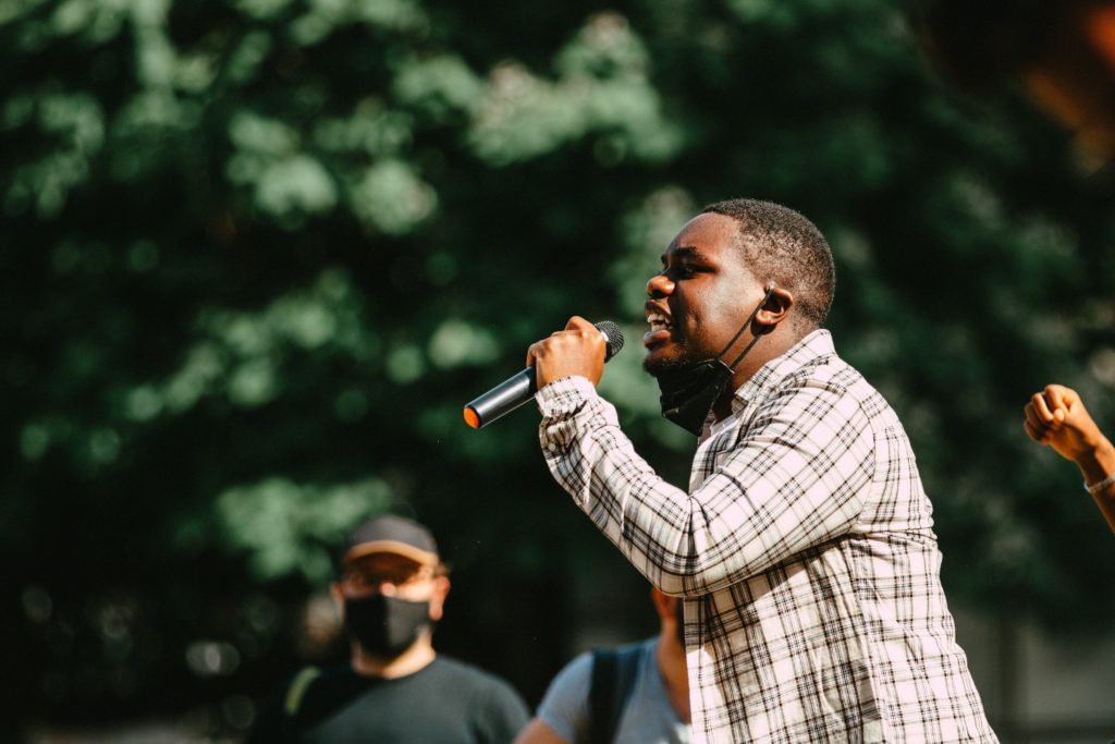 Black college-aged male passionately speaks into a microphone