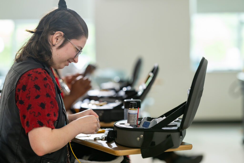 Young woman working on fiber optics at her desk.