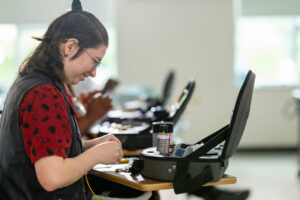 Young woman working on fiber optics at her desk.