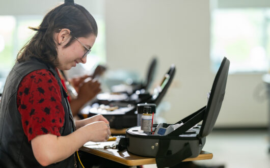 Young woman working on fiber optics at her desk.